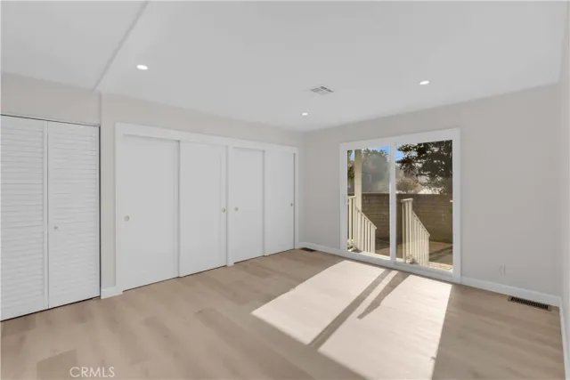 a view of an empty room with wooden floor and closet
