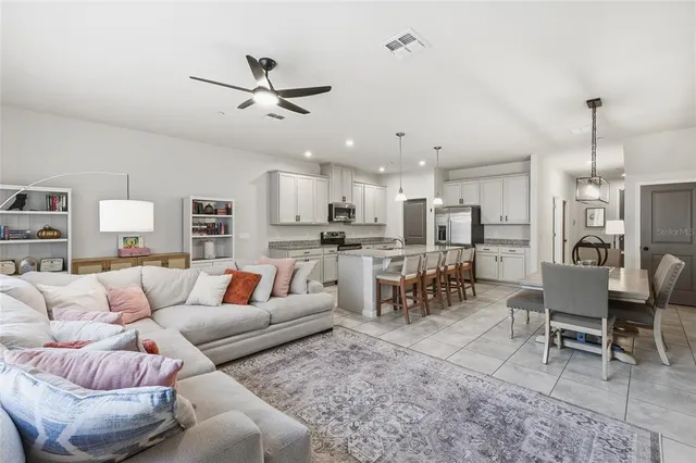 a living room with furniture kitchen view and a chandelier