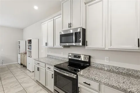 a kitchen with granite countertop white cabinets and stainless steel appliances
