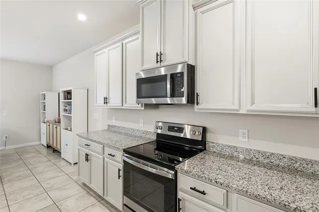 a kitchen with granite countertop white cabinets and stainless steel appliances