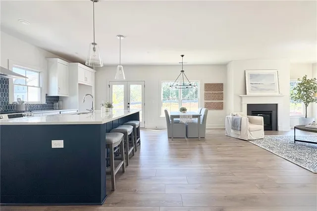 a kitchen with stainless steel appliances granite countertop a stove a sink dishwasher a refrigerator white cabinets and wooden floor