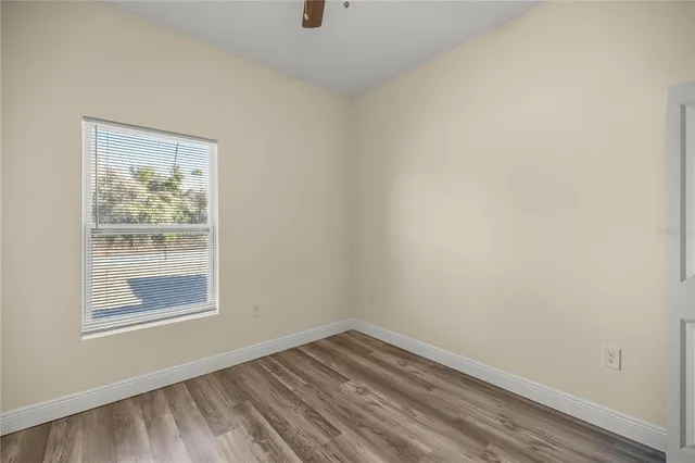 a view of an empty room with wooden floor and a window