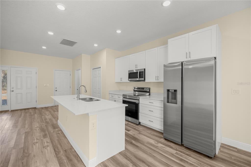 13745 Southwest 43rd Circle Ocala, FL 34473 - Photo 6 of 25 a kitchen with white cabinets and stainless steel appliances