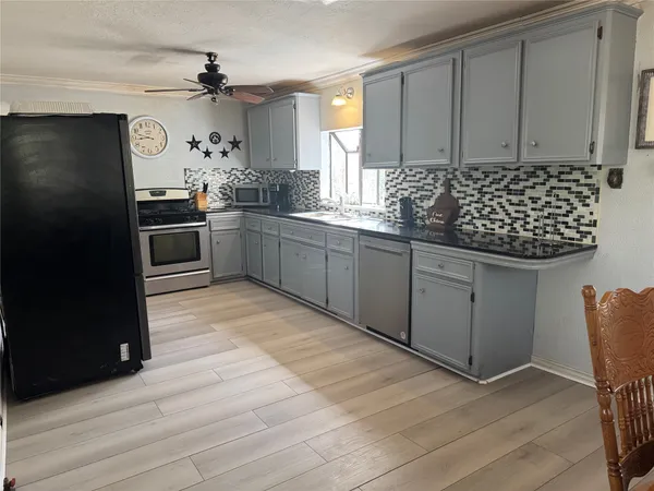 a kitchen with granite countertop a sink cabinets and stainless steel appliances