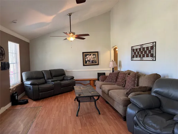 a living room with furniture a ceiling fan and a wooden floor