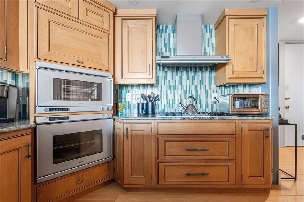 65 East India Row, Unit 26F Boston, MA 02110 - Photo 14 of 27 a kitchen with granite countertop cabinets stainless steel appliances and a counter space
