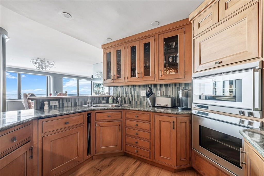 65 East India Row, Unit 26F Boston, MA 02110 - Photo 16 of 27 a kitchen with granite countertop cabinets stainless steel appliances and a sink