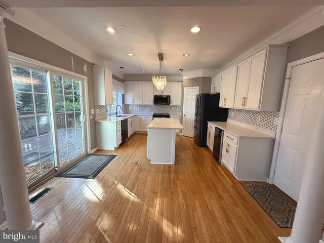 a large kitchen with stainless steel appliances a refrigerator a sink dishwasher a stove and white countertops with wooden floor