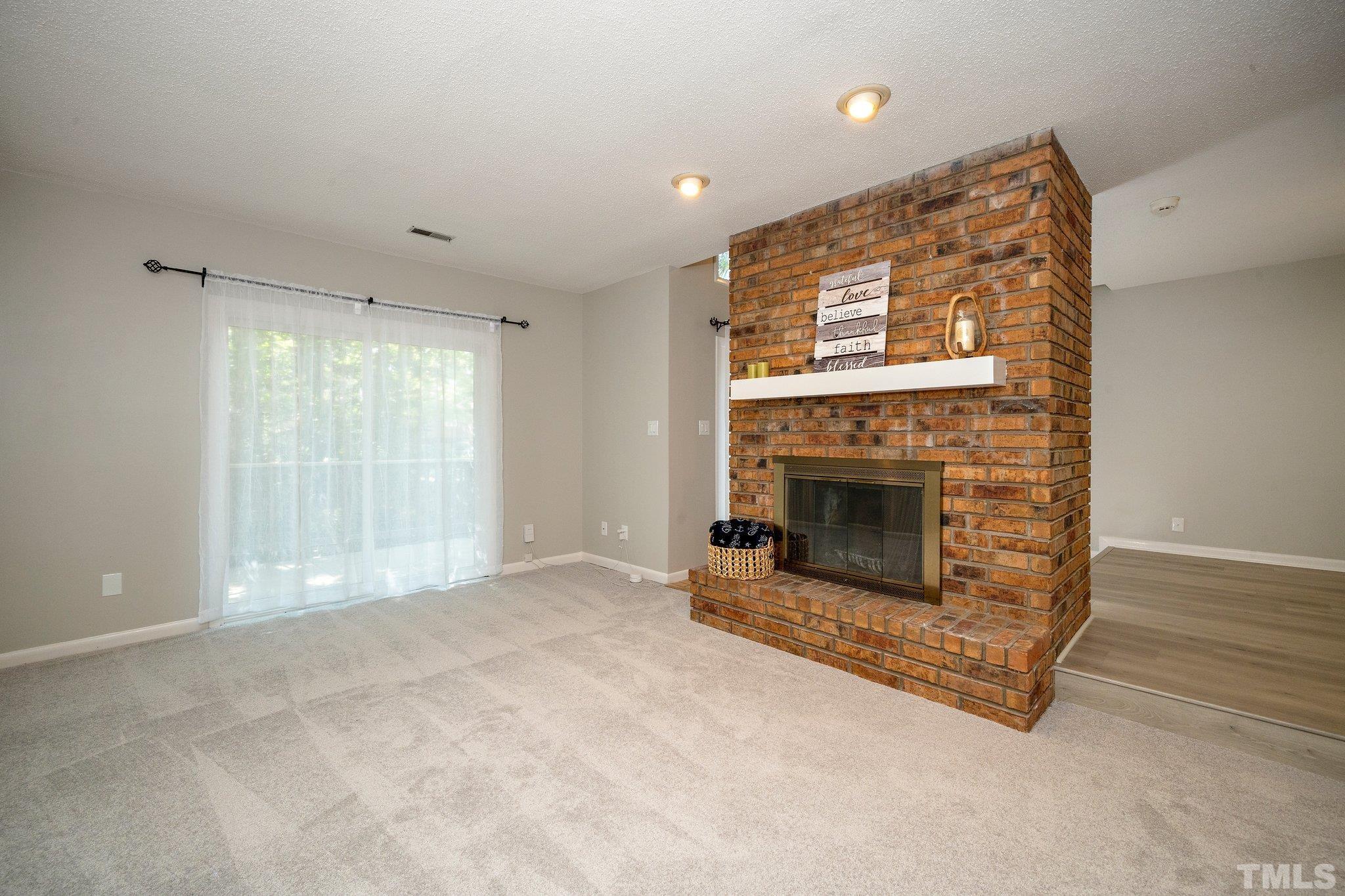 4353 Southwind Drive Raleigh, NC 27613 - Photo 4 of 23 a view of an empty room with a fireplace and a window