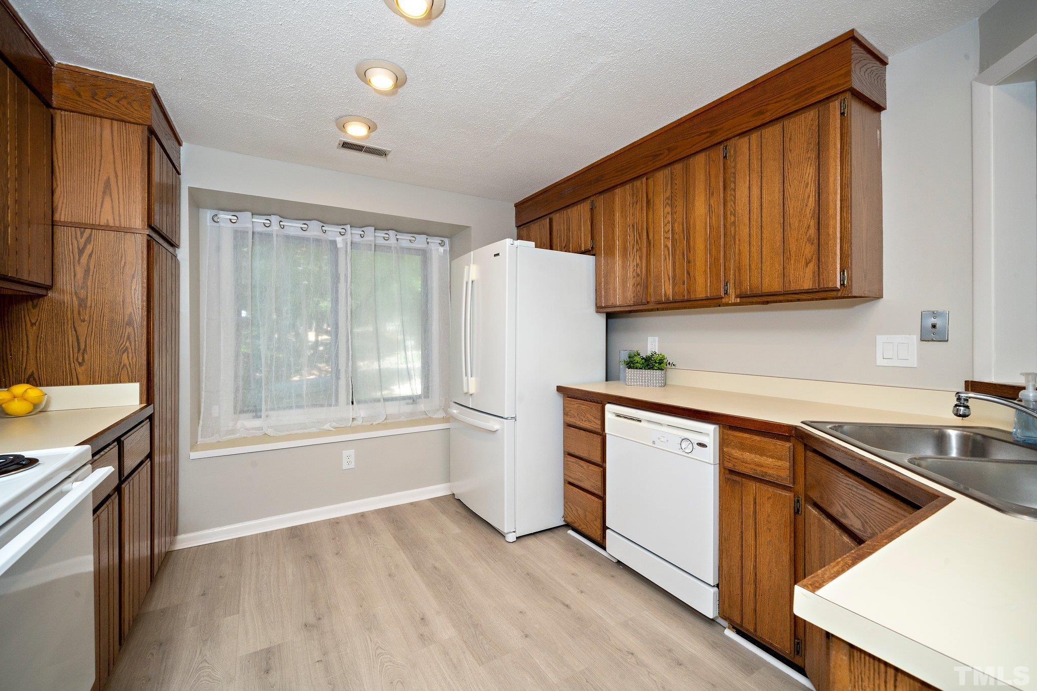 4353 Southwind Drive Raleigh, NC 27613 - Photo 8 of 23 a kitchen with a sink a refrigerator and cabinets