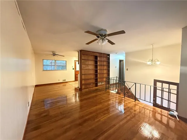 a view of an empty room with window and wooden floor