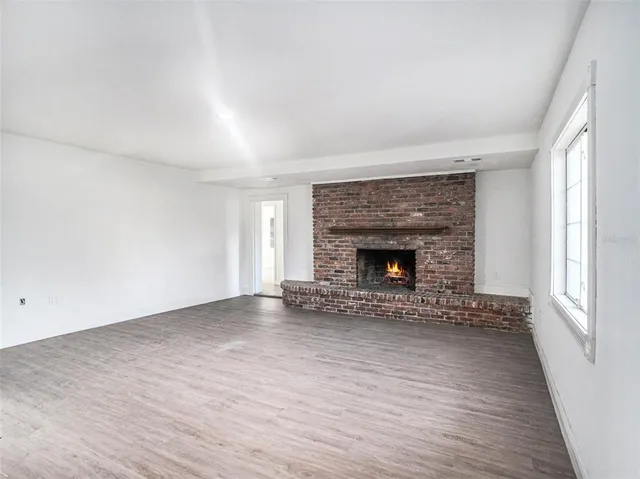 an empty room with wooden floor and fireplace