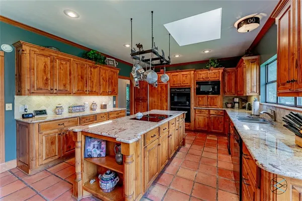 a kitchen with stainless steel appliances granite countertop a stove a sink dishwasher and a refrigerator with wooden cabinets