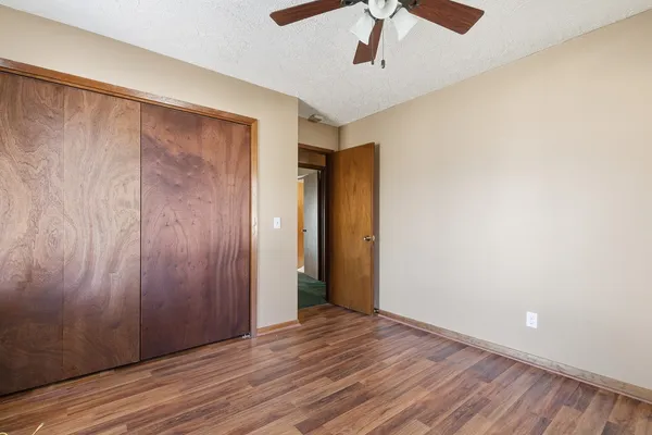 an empty room with wooden floor and a ceiling fan