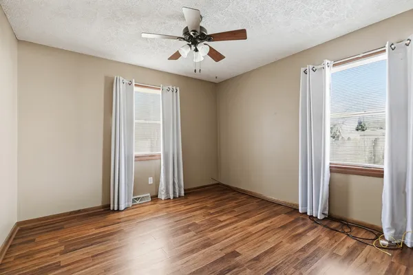 an empty room with wooden floor and windows