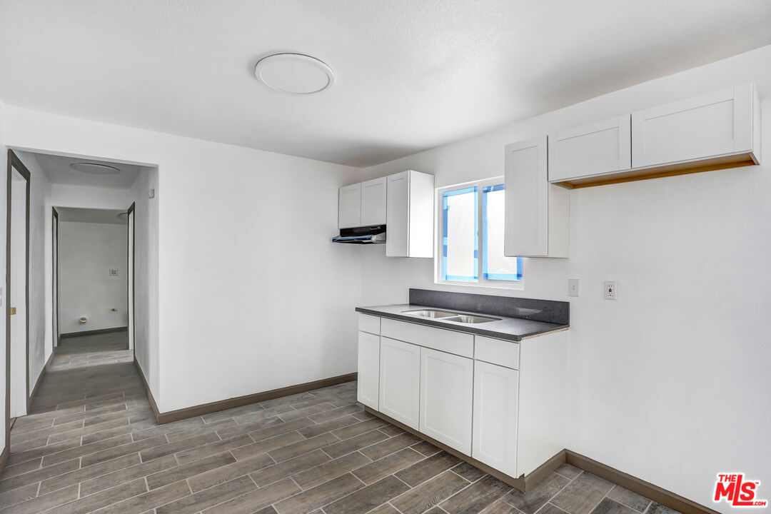 7594 Peters Street Riverside, CA 92504 - Photo 10 of 16 a kitchen with granite countertop a sink cabinets and wooden floor