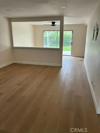 an empty room with wooden floor a ceiling fan and windows