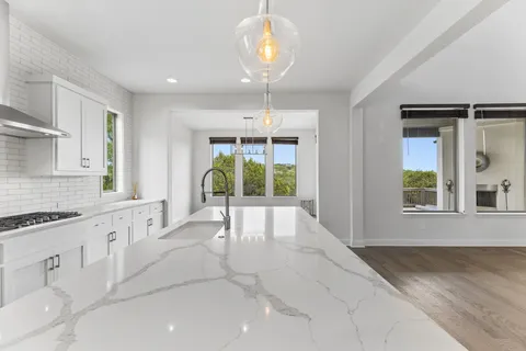 a large white kitchen with granite countertop a large window and white appliances