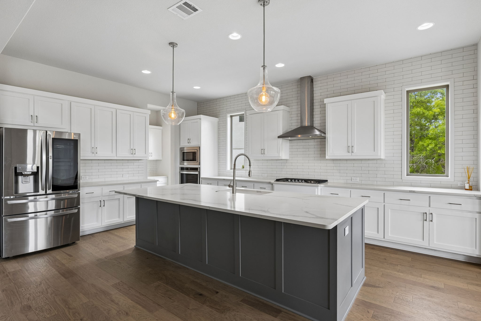 7212 Celebration Court Leander, TX 78645 - Photo 19 of 39 a kitchen with kitchen island white cabinets and stainless steel appliances