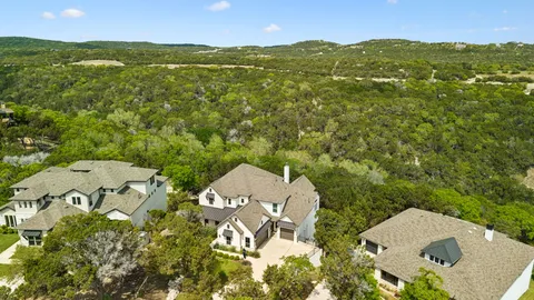 an aerial view of residential houses with outdoor space and trees all around
