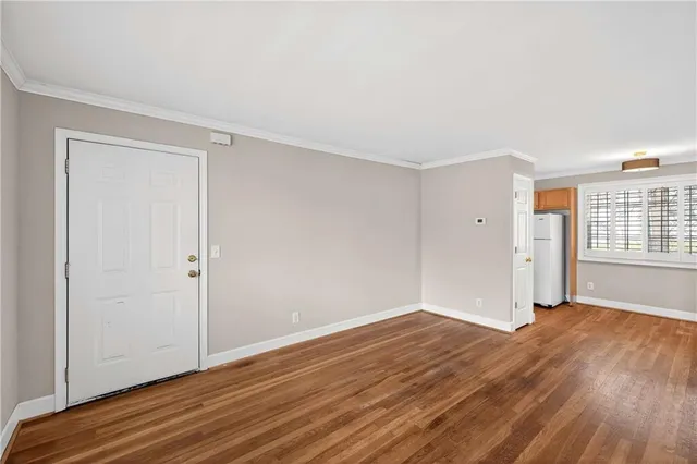 a view of an empty room with wooden floor and a window