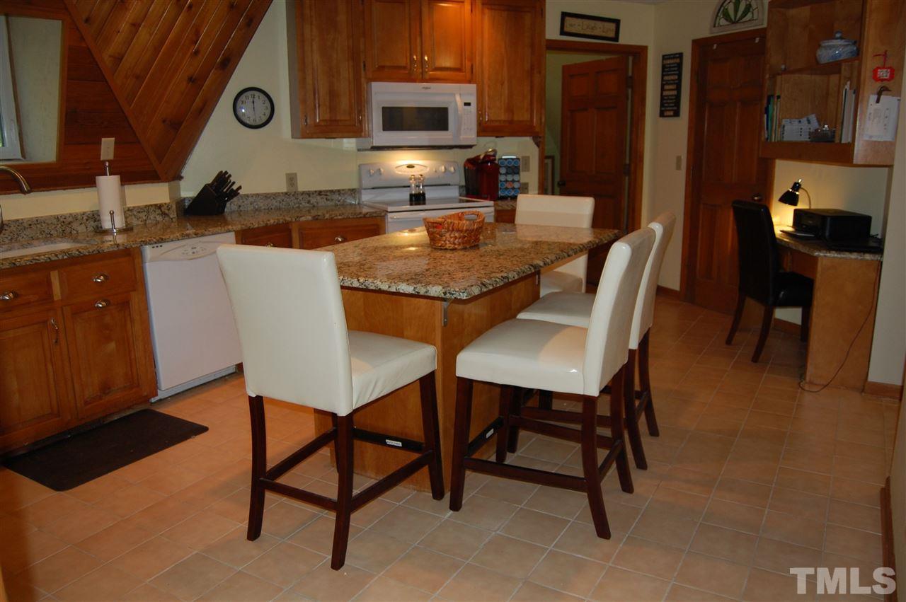 1121 Batchelor Road Apex, NC 27523 - Photo 10 of 30 Kitchen w/tile flooring, pantry and 1 cabinet pantry, granite counter tops, movable island & built-in-desk, Refrigerator (5 yrs) conveys, lots of shelving & cabinets w/nook for TV!