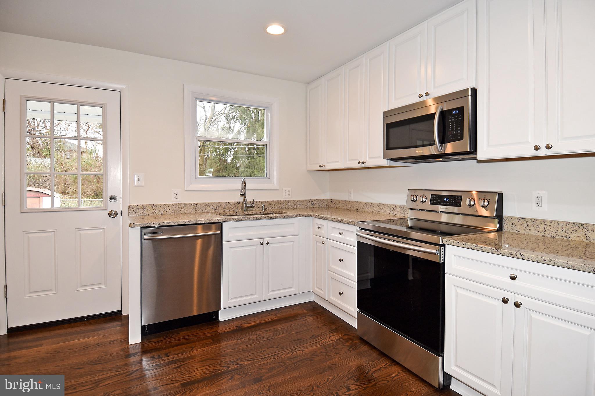 8609 Woodspring Road Randallstown, MD 21133 - Photo 11 of 43 a kitchen with granite countertop white cabinets and stainless steel appliances