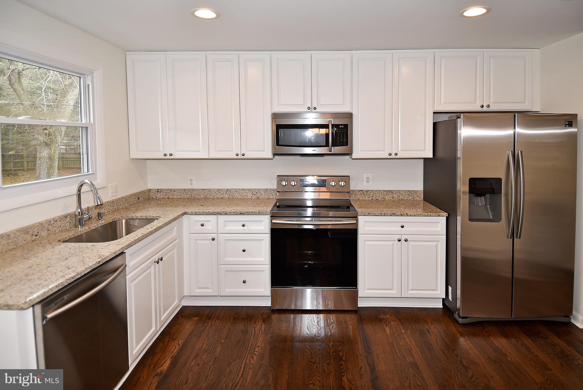 8609 Woodspring Road Randallstown, MD 21133 - Photo 12 of 43 a kitchen with stainless steel appliances granite countertop a refrigerator a stove a sink and white cabinets