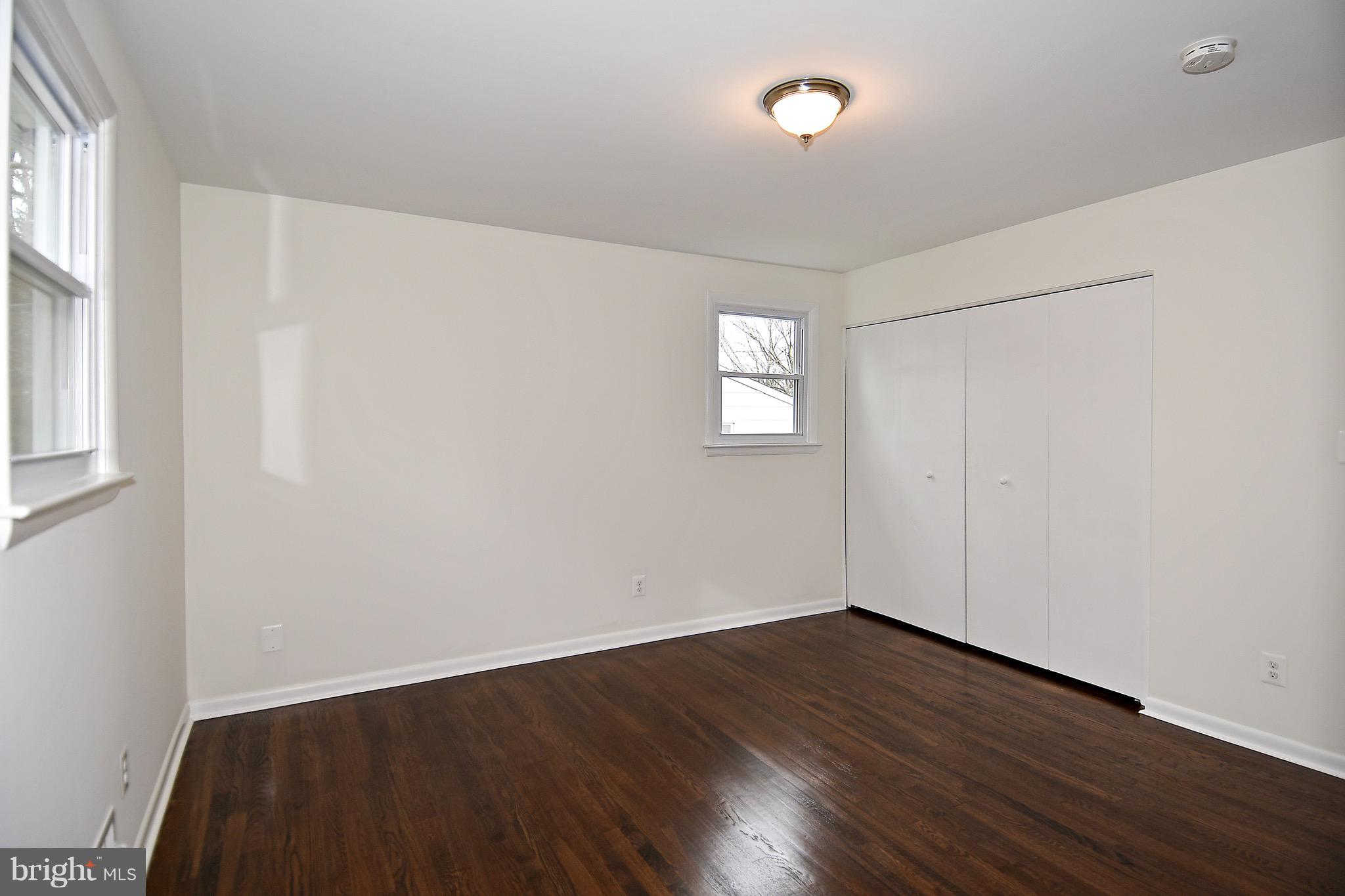 8609 Woodspring Road Randallstown, MD 21133 - Photo 16 of 43 an empty room with wooden floor and windows