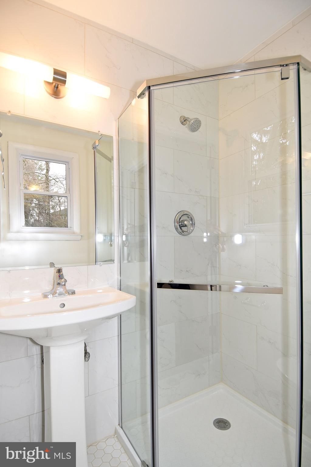 8609 Woodspring Road Randallstown, MD 21133 - Photo 20 of 43 a bathroom with a shower sink vanity and mirror
