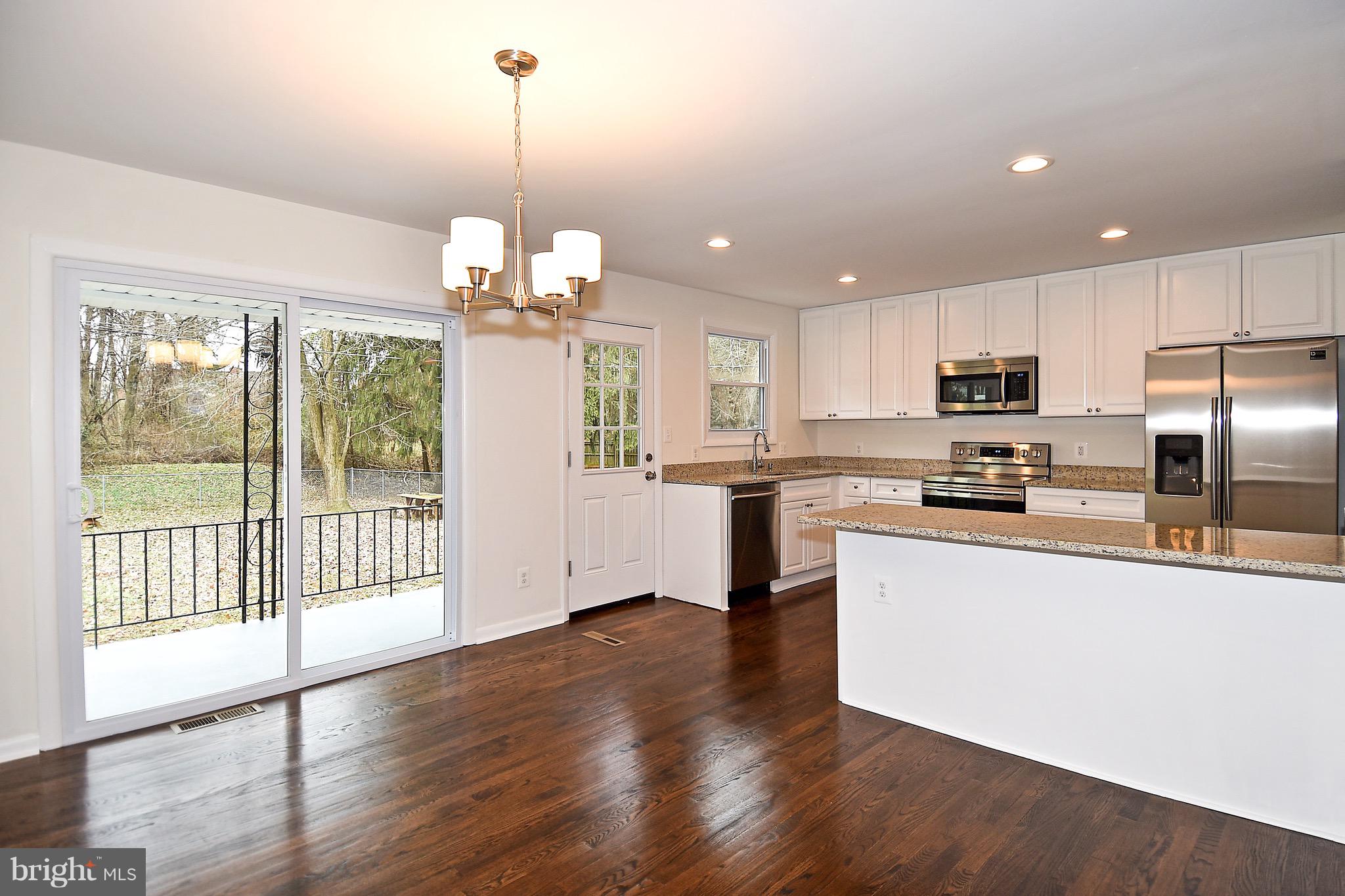 8609 Woodspring Road Randallstown, MD 21133 - Photo 8 of 43 a kitchen with stainless steel appliances granite countertop a refrigerator a sink dishwasher a stove and white cabinets with wooden floor