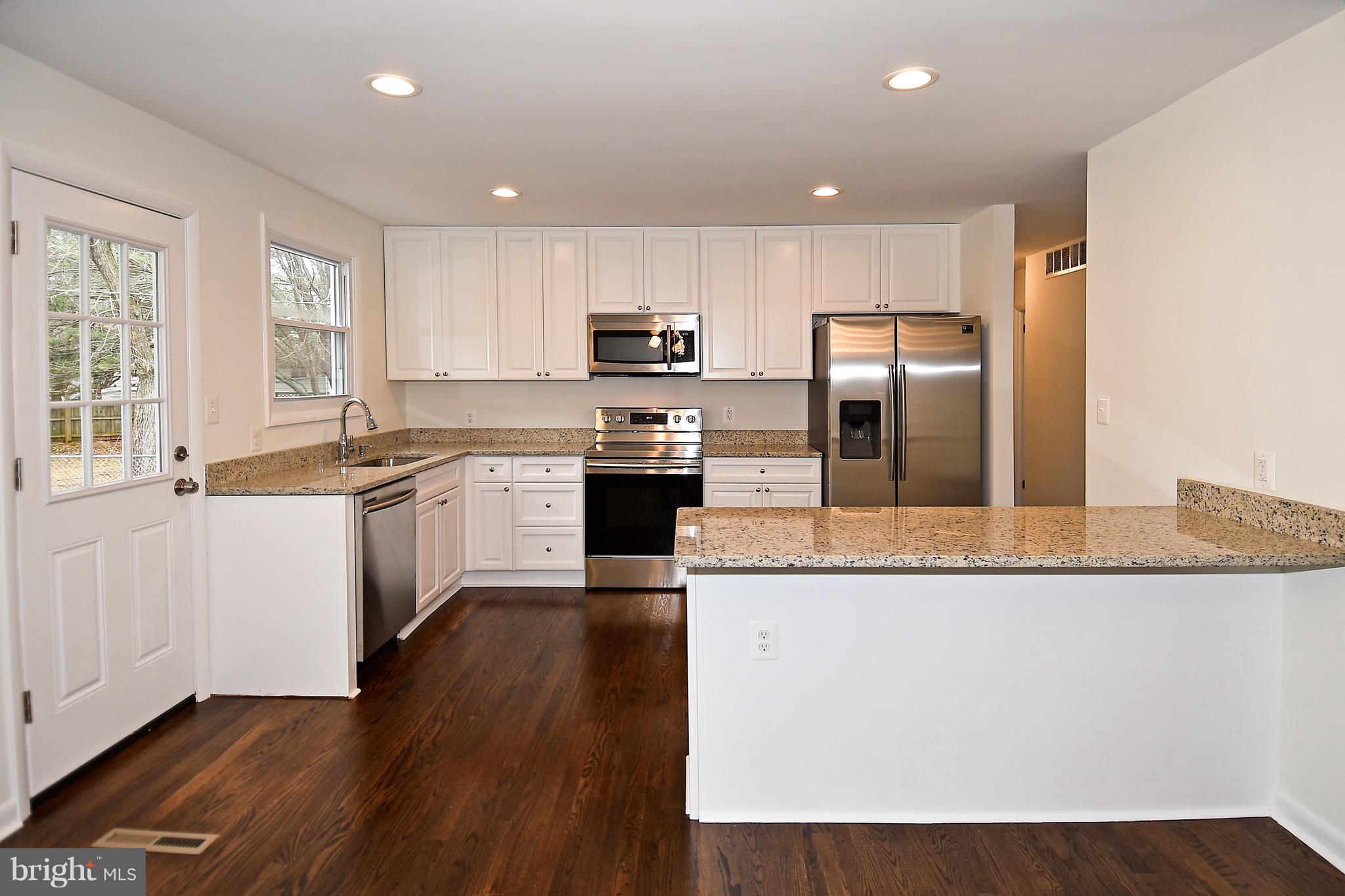 8609 Woodspring Road Randallstown, MD 21133 - Photo 10 of 43 a kitchen with stainless steel appliances granite countertop a sink a stove a refrigerator and island with wooden floor