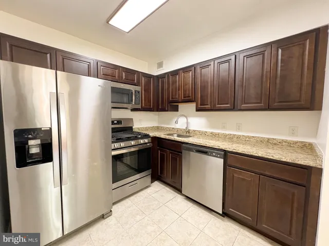 a kitchen with granite countertop a refrigerator stove and cabinets