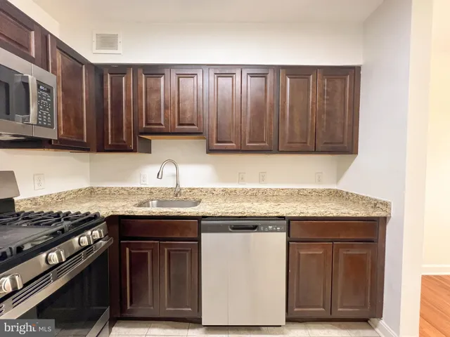 a kitchen with granite countertop wooden cabinets a sink and a stove
