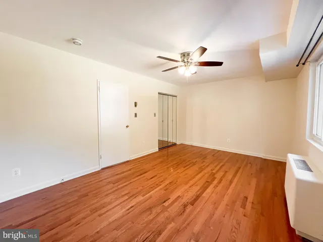 a view of empty room with wooden floor and fan