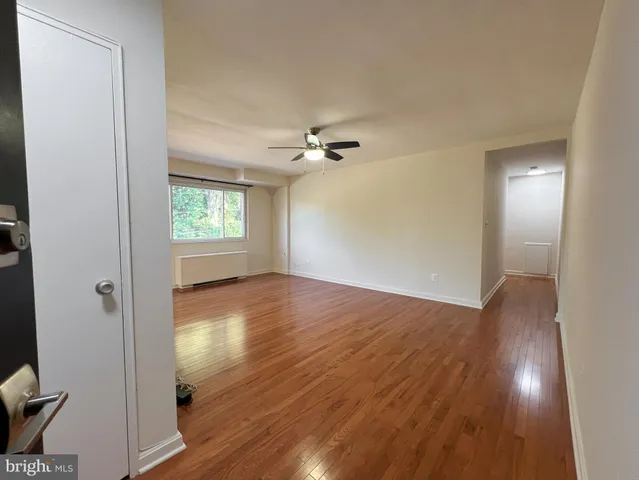 a view of an empty room with wooden floor and a window
