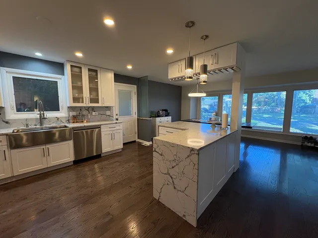 a large kitchen with stainless steel appliances kitchen island a large counter top a sink a stove and a refrigerator