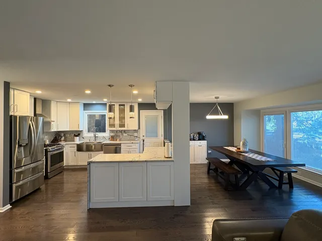 a view of a kitchen with dining table stainless steel appliances and wooden floor