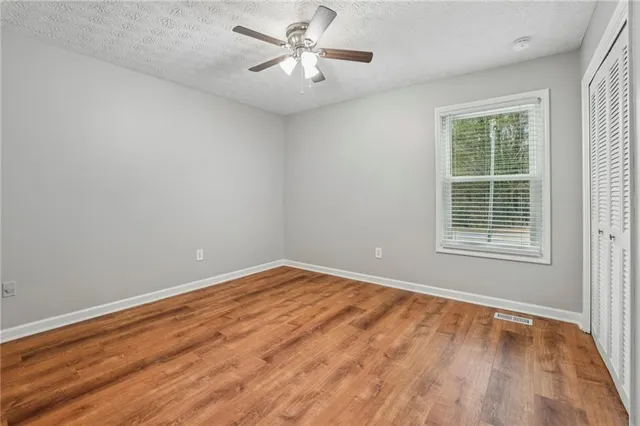 a view of an empty room with a window and wooden floor