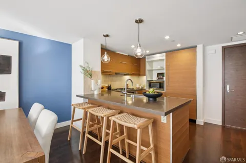 a kitchen with stainless steel appliances kitchen island granite countertop a refrigerator a stove and a sink with wooden floor