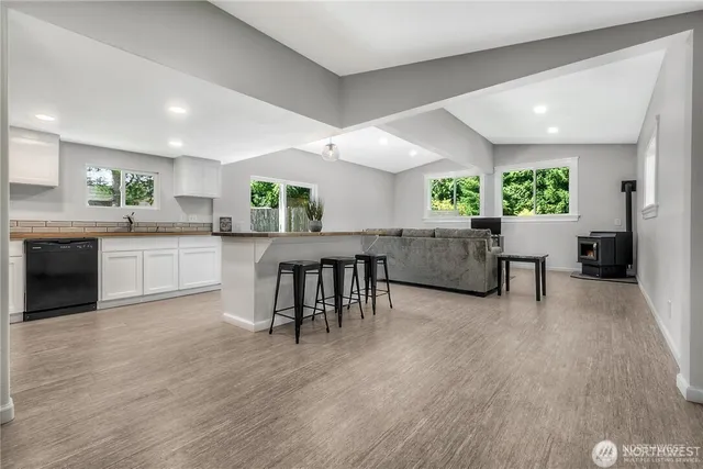 a open kitchen with granite countertop a stove top oven a sink a dining table and chairs