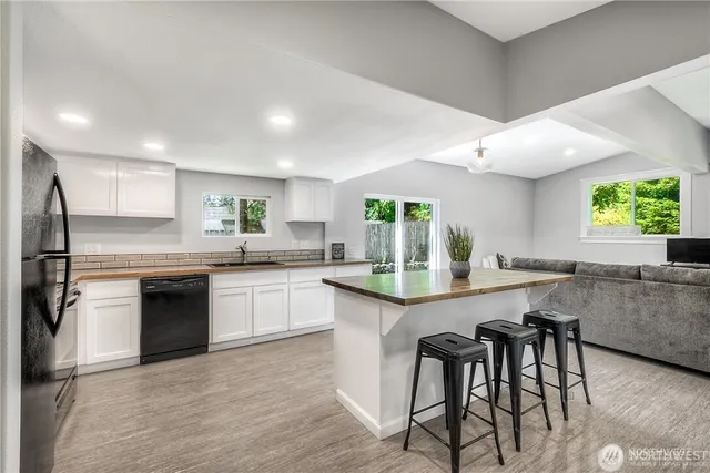 a kitchen with granite countertop a table chairs stove a sink dishwasher and cabinets