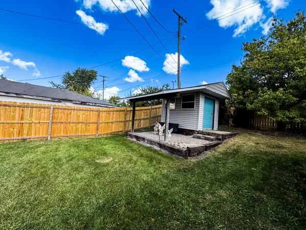 a view of a backyard with couches plants and large trees