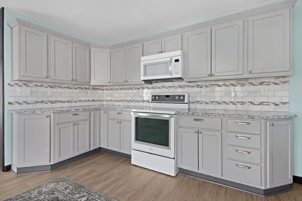 a kitchen with granite countertop white cabinets and white appliances