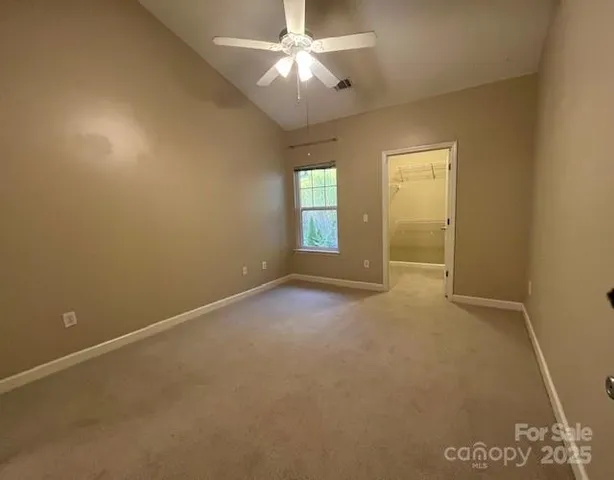 an empty room with a chandelier fan and windows