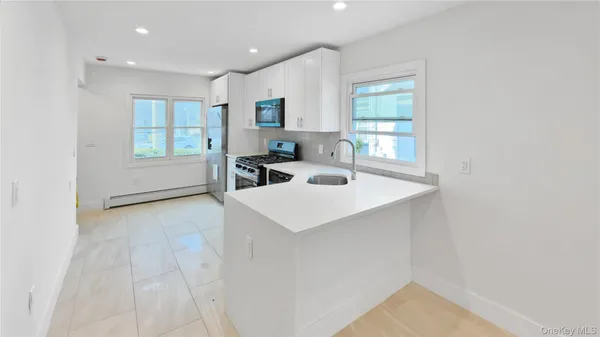 a view of a kitchen with a sink and dishwasher with white cabinets