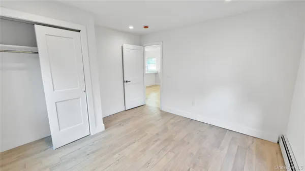 a view of an empty room with wooden floor and closet