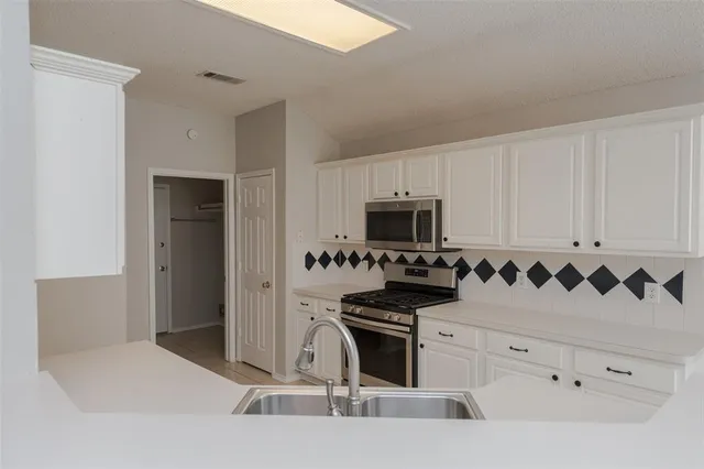 a kitchen with white cabinets and stainless steel appliances