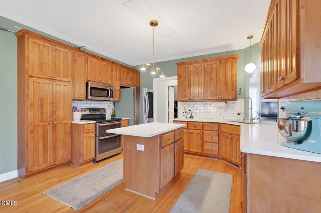 a kitchen with stainless steel appliances granite countertop a stove a sink dishwasher and a refrigerator with wooden floor