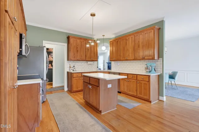 a kitchen with stainless steel appliances granite countertop a sink a stove top oven a refrigerator cabinets and wooden floor